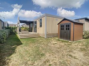 una pequeña casa con una puerta marrón en un patio en Mobil-Home Jullouville, 3 pièces, 4 personnes - FR-1-361A-2 en Jullouville-les-Pins