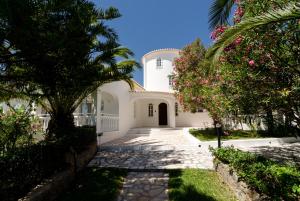 uma casa branca com palmeiras e uma passagem em Villa Do Monte em Monte Raposo