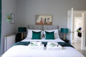 um quarto com uma grande cama branca com almofadas verdes em 2 Bed Apartment by AV Stays Short Lets & Serviced Accommodation Sittingbourne Kent em Kent