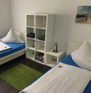 een slaapkamer met 2 bedden en een boekenplank bij HOSTEL 66 Bremerhaven Geestland in Imsum