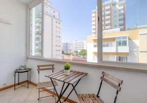 a balcony with a wooden table and two benches at Sea-Front near Vilamoura - with AC, WiFi, Netflix in Quarteira