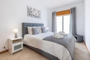 a bedroom with a large bed and a window at Sea-Front near Vilamoura - with AC, WiFi, Netflix in Quarteira