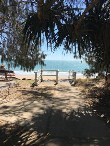 einen Weg zum Strand mit einer Bank und dem Meer in der Unterkunft Seabreeze at Silver Sands Hervey Bay in Hervey Bay