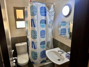 a bathroom with a toilet and a sink and a shower curtain at DeadSea Accommodation with AC in Sowayma