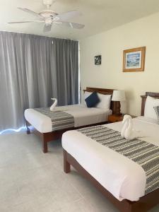 een hotelkamer met 2 bedden en een plafondventilator bij Hotel Villas Ema in Zihuatanejo