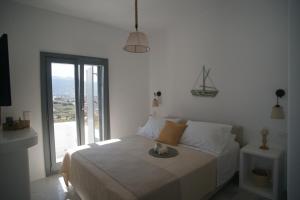 a white bedroom with a bed and a large window at Krotiri View Paros in Krotiri