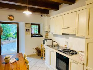 a kitchen with white cabinets and a wooden table at Cottage Nonnannita in Frascara