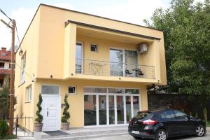 a yellow house with a car parked in front of it at Cavleski rooms in Prilep