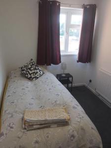 a bed in a bedroom with a window and a bedspread at 3 bedrtoom comfortable house in Houghton Regis