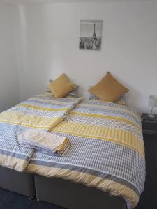 Bett mit gelber und blauer Bettwäsche und Kissen in der Unterkunft 3 bedrtoom comfortable house in Houghton Regis