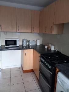 a kitchen with a stove and a microwave at 3 bedrtoom comfortable house in Houghton Regis