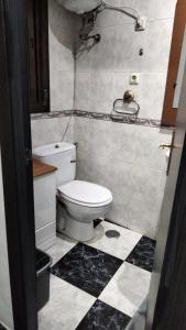 Un baño con inodoro y suelo a cuadros en blanco y negro. en Lunarota Home, en Madrid