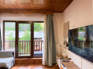 een woonkamer met een televisie en een balkon bij Ático Dúplex Con Increibles Vistas a La Valle De Incles - Parking Gratis in Incles