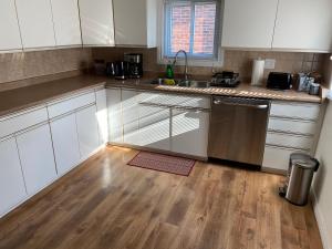 a kitchen with white cabinets and a wooden floor at Windsor Airport Accommodation in Windsor