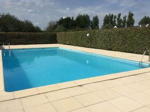 a large blue swimming pool next to a hedge at Appartement Erdeven, 3 pièces, 4 personnes - FR-1-397-68 in Erdeven
