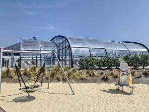 a beach with two surfboards in the sand in front of a building at Mobil-Home Jullouville, 3 pièces, 4 personnes - FR-1-361A-59 in Jullouville-les-Pins