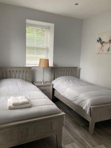 1 dormitorio con 2 camas y ventana en Gwaelodygarth Lodge en Merthyr Tydfil