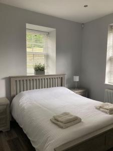 a bedroom with a white bed with two towels on it at Gwaelodygarth Lodge in Merthyr Tydfil