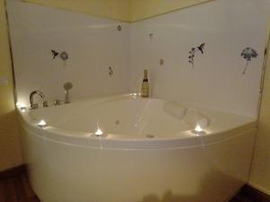 a bath tub with lights and a bottle of champagne at O fogar da musiña in Maside