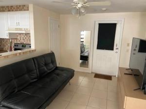 a living room with a black couch and a television at Cozy Private House near Miami Airport - Free parking - 02 in Miami