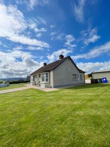 a house with a green lawn in front of it at The Myles' Self-Catering Cottage - 4 Stars in Greencastle