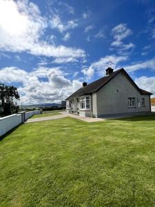 a house with a large grassy yard in front of it at The Myles' Self-Catering Cottage - 4 Stars in Greencastle