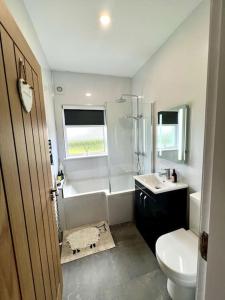 a bathroom with a tub and a sink and a toilet at The Myles' Self-Catering Cottage - 4 Stars in Greencastle