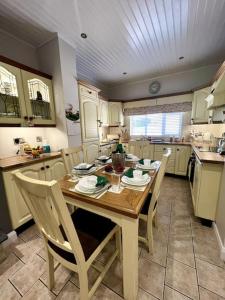 a kitchen with a wooden table and chairs in it at The Myles' Self-Catering Cottage - 4 Stars in Greencastle