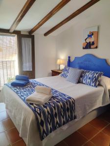 1 dormitorio con 1 cama grande con sábanas azules y blancas en Masía de San Juan, casa rural renovada en Castillo con piscina y Aire Acondicionado, en Segorbe