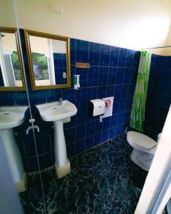 La salle de bains est pourvue de carrelage bleu, d'un lavabo et de toilettes. dans l'établissement Hostel de Haan, à Jacó
