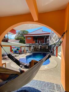 una persona sdraiata su un'amaca accanto alla piscina di Hostel de Haan a Jacó