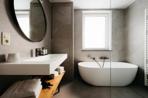bagno con vasca, lavandino e specchio di The Edgewater Suites - Park View a Namur