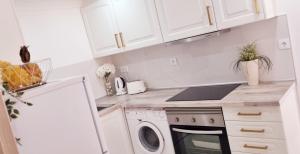 uma cozinha com armários brancos e uma máquina de lavar e secar roupa em Casa Dourada em Alvor