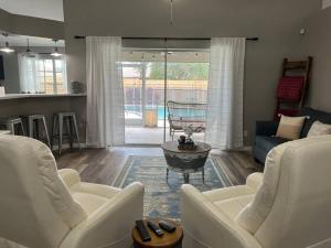 a living room with two white chairs and a table at Southern Charm meets sunny FL fun! Home with pool and central to everything. in Cape Coral