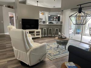 a living room with white chairs and a flat screen tv at Southern Charm meets sunny FL fun! Home with pool and central to everything. in Cape Coral