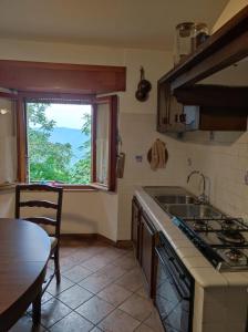 een keuken met een wastafel, een tafel en een raam bij La grotta dei nonni in Sassa