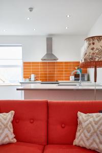 a red couch sitting in front of a kitchen at Binks - Seafront 1 bed first floor apartment in Cleethorpes