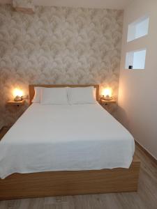 a bedroom with a large white bed with two lamps at La Lunita in Valverde