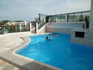 two people in a swimming pool on top of a building at Loft na Prainha - Arraial do Cabo in Arraial do Cabo
