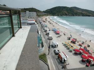 a beach with a bunch of umbrellas and people at Loft na Prainha - Arraial do Cabo in Arraial do Cabo