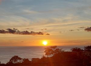 een zonsondergang boven de oceaan met de zon in de lucht bij Sea View Guest Accommodation in Roseau