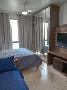 a bedroom with a bed and a flat screen tv at Loft na Prainha - Arraial do Cabo in Arraial do Cabo