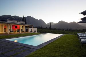 a swimming pool in front of a house with mountains at La Providence in Franschhoek
