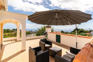 a patio with chairs and an umbrella on a roof at Noite´s House - Prazeres in Prazeres