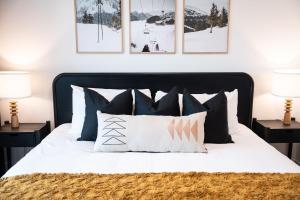 a bedroom with a black and white bed with pillows at The Selkirk House by Revelstoke Vacations in Revelstoke