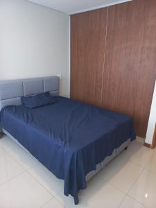 1 dormitorio con cama azul y pared de madera en PIHARE II, en Santa Cruz de la Sierra