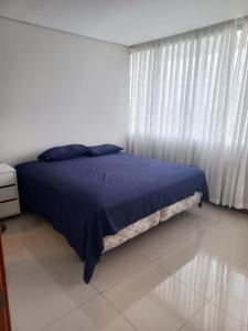 Schlafzimmer mit einem Bett mit blauer Bettwäsche und einem Fenster in der Unterkunft PIHARE II in Santa Cruz de la Sierra