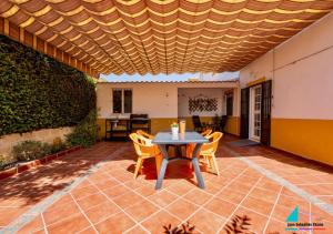 eine Terrasse mit einem Tisch und Stühlen unter einer Holzdecke in der Unterkunft Casa Juan Sebastian Elcano in Gelves