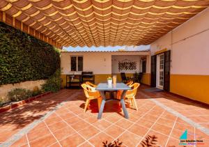 a patio with a table and chairs under a wooden ceiling at Casa Juan Sebastian Elcano in Gelves
