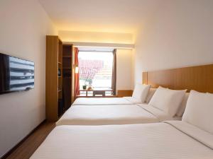 ein Hotelzimmer mit 2 Betten und einem Fenster in der Unterkunft Ibis Singapore on Bencoolen in Singapur